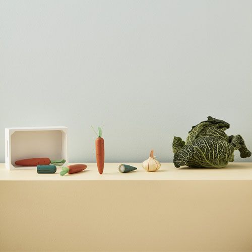 Kids Concept houten speelgoedgroenten, waaronder wortels, knoflook en een stoffen kool, op een gele plank.
