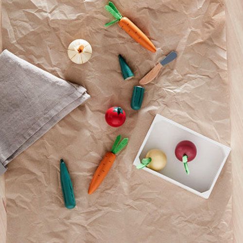 Kids Concept houten speelgoedgroenten en een houten mes op bruin papier, met wortels, knoflook en een tomaat.