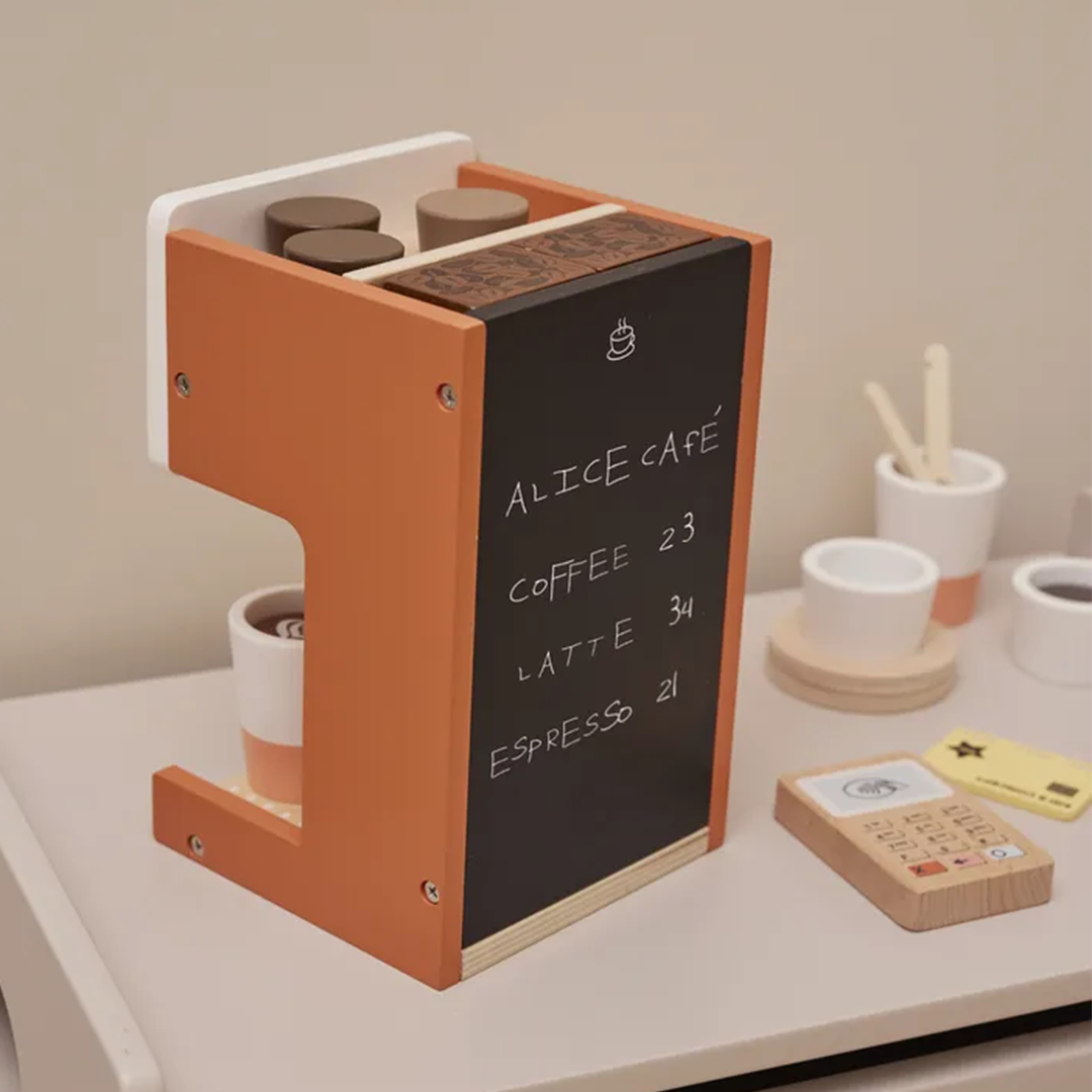 Zijaanzicht van de Kids Concept houten koffiemachine speelset met een krijtbord waarop 'Alice Café' en prijzen staan, naast kopjes en een betaalautomaat.