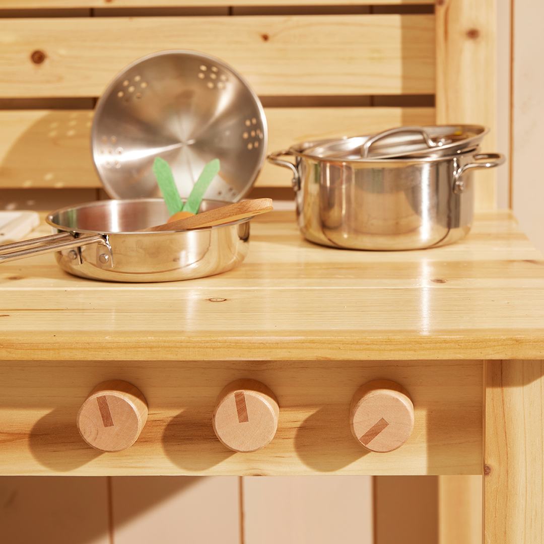 Kids Concept speelgoed kookgerei van roestvrij staal op een houten speelkeuken met draaiknoppen.