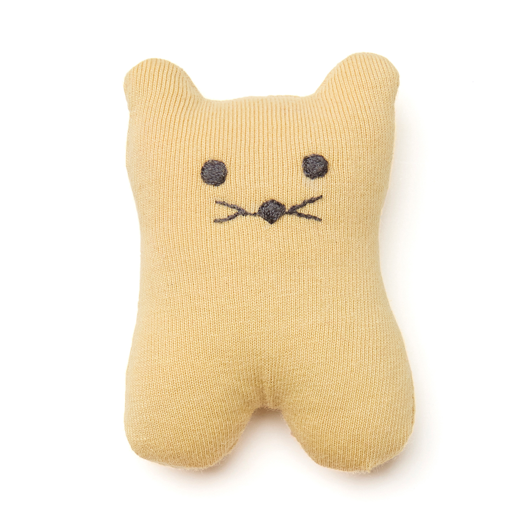 Een klein geel gebreid kattenknuffeltje met geborduurde ogen en snorharen.