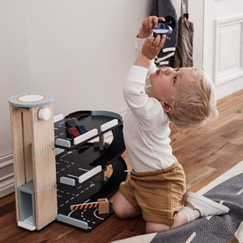 Een kind speelt met de Kids Concept houten parkeergarage Aiden en houdt de helikopter omhoog.