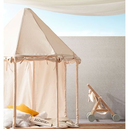 Kids Concept beige speeltent paviljoen buiten op een houten vlonder met kussens en een poppenwagen.