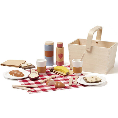 De Kids Concept houten picknick speelset met mand en alle speelgoedeten, bestek en servies uitgestald op een rood geruite mat.