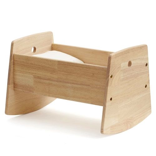 Kids Concept houten poppenwieg met een wit kussentje, schuin van voren gefotografeerd.