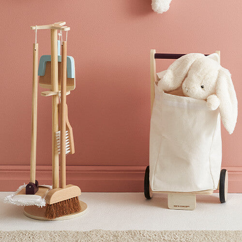 De Kids Concept houten schoonmaakset Kid's Hub staat naast een wit konijnenknuffel in een stoffen mand op wielen.