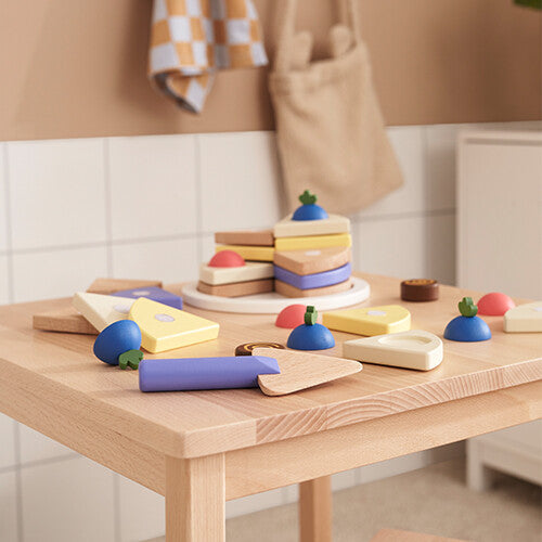 Kids Concept houten speelgoedtaart set op een houten tafel, met de taart deels gemonteerd en losse stukken ernaast.
