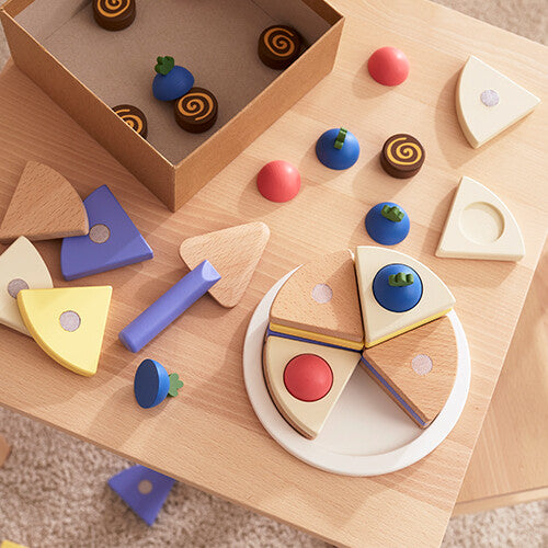 Kids Concept houten speelgoedtaart set op een houten tafel, met de taart deels gemonteerd en losse stukken in een doos.