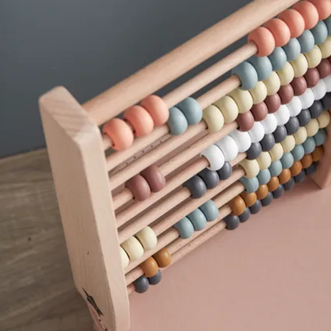 Kids Concept houten telraam met veelkleurige kralen, schuin gefotografeerd op een roze ondergrond.
