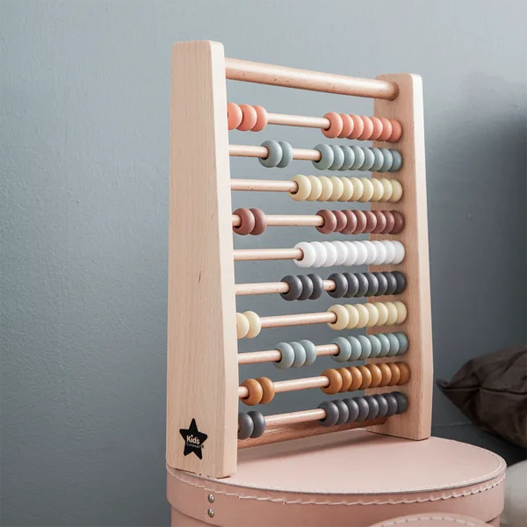 Kids Concept houten telraam met veelkleurige kralen, staand op een roze kruk.