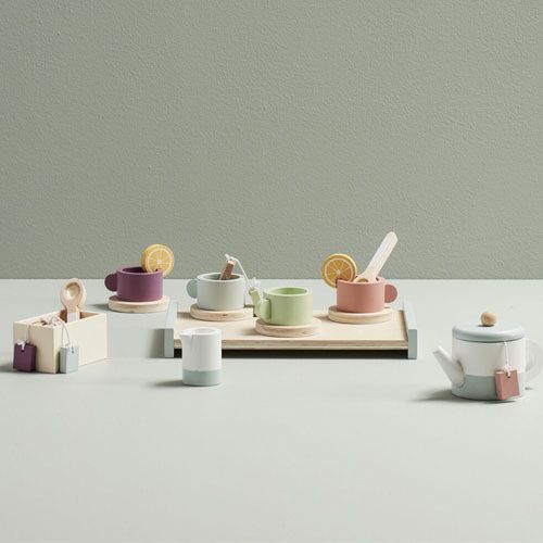 De Kids Concept houten theeset bistro met theepot, vier kopjes en diverse accessoires op een lichtgroene ondergrond.