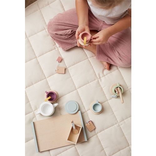 Een kind speelt met de Kids Concept houten theeset bistro op een gewatteerde speelmat, van bovenaf gezien.