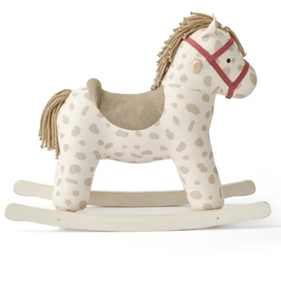 Kids Concept hobbelpaard met beige stof met bruine stippen en rode teugels, van de zijkant gefotografeerd.
