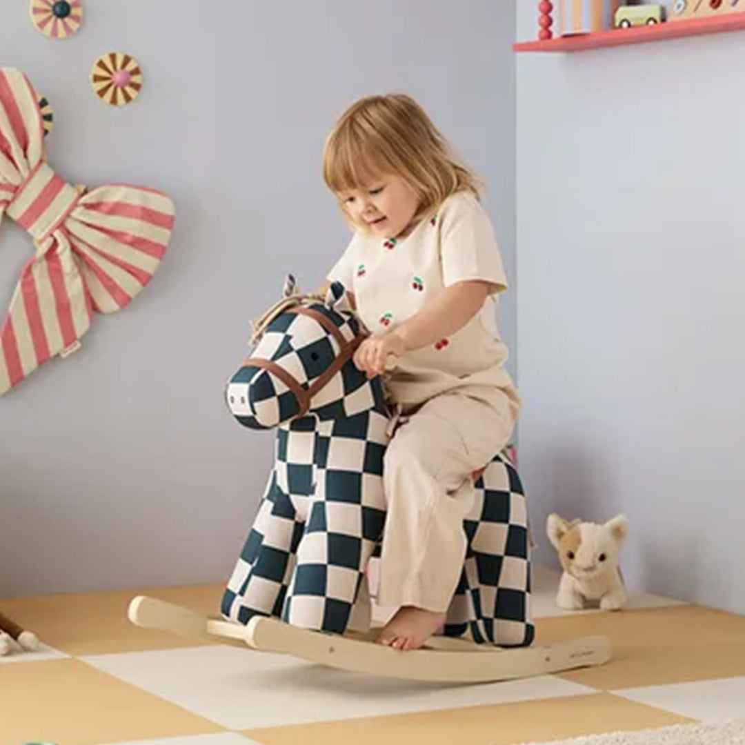Een kind zit op het Kids Concept hobbelpaard met geruit patroon in een speelkamer.