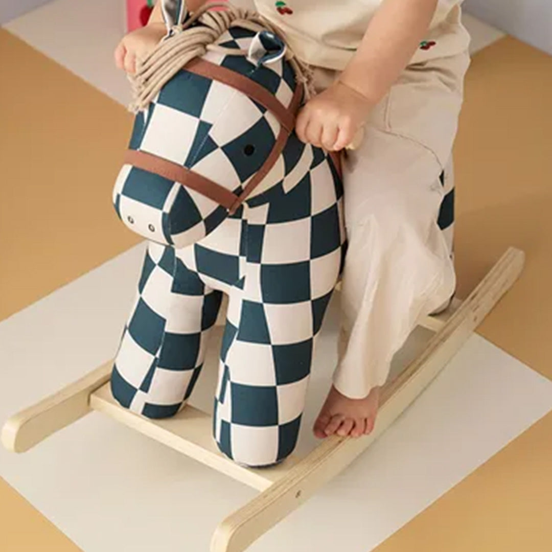 Detailfoto van een kind dat op het Kids Concept hobbelpaard met geruit patroon zit.