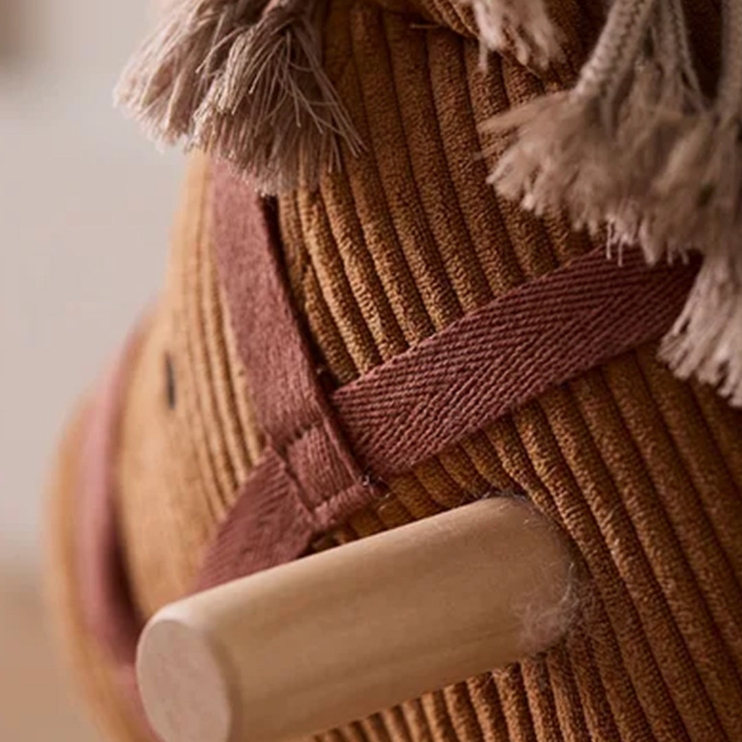 Detail van de kop van het bruine corduroy hobbelpaard met houten handvat.