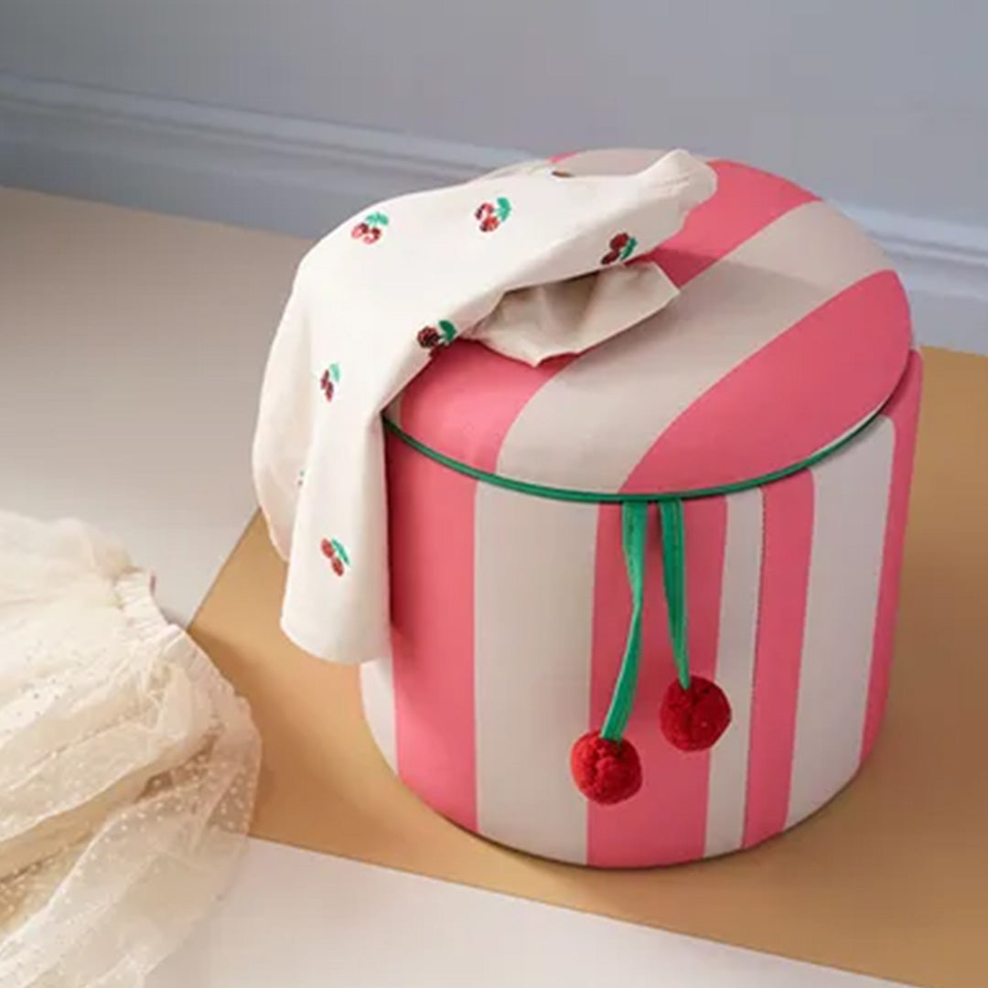 kids concept opbergpoef met roze en witte strepen en een gesloten deksel, met een doek met kersenprint erop.