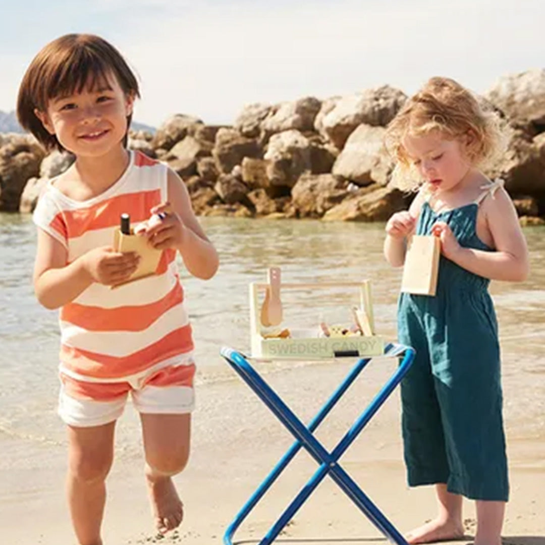 Twee kinderen spelen met de Kids Concept houten snoepwinkel speelset op een strand.