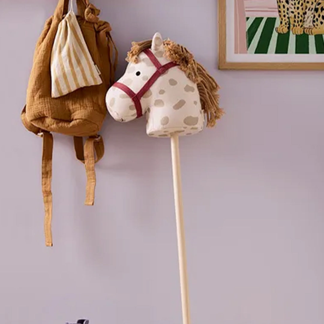 Het Kids Concept stokpaard Dotty staat in een kinderkamer naast een rugzak.