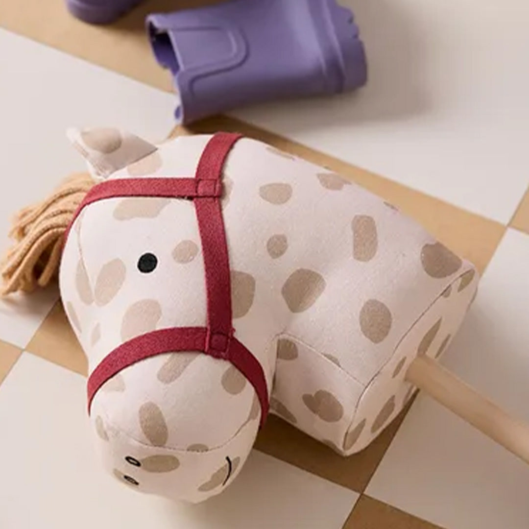 Detail van de kop van het Kids Concept stokpaard Dotty met beige stof met stippen en rood hoofdstel.