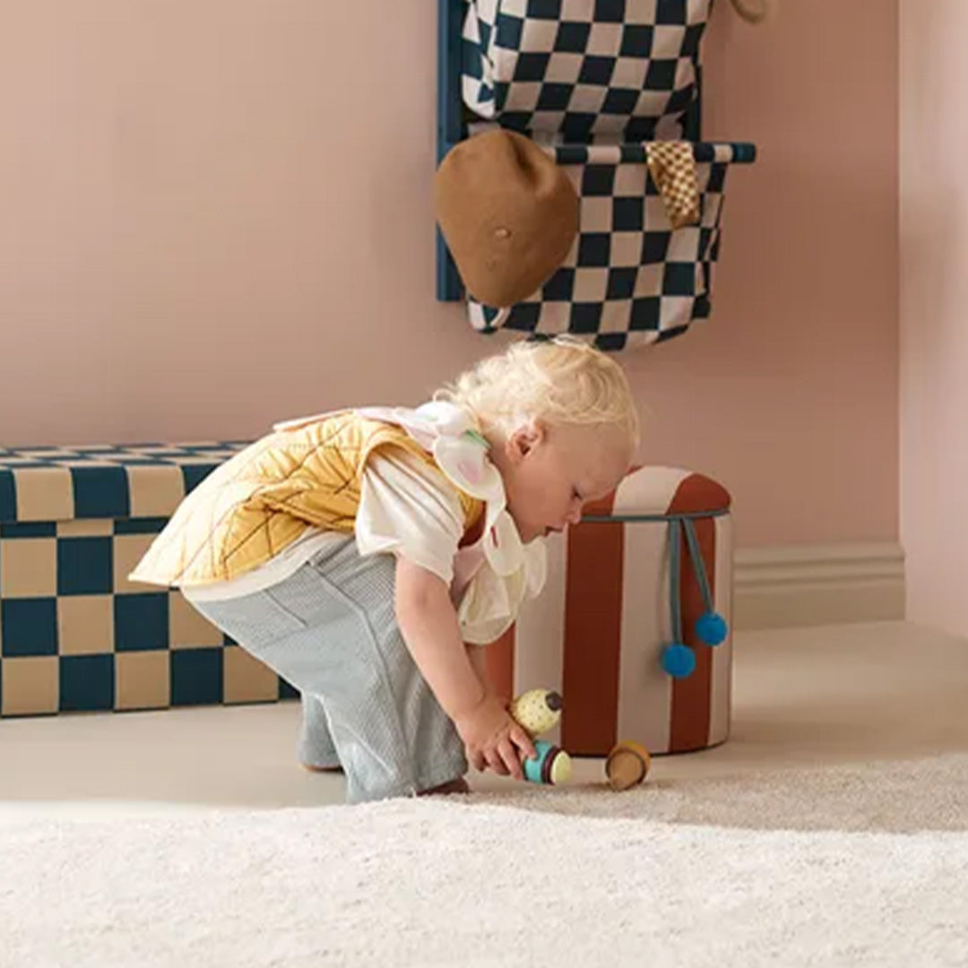Een kind draagt de kids concept ijsje verkleedkleding en speelt op de grond met een speeltje.