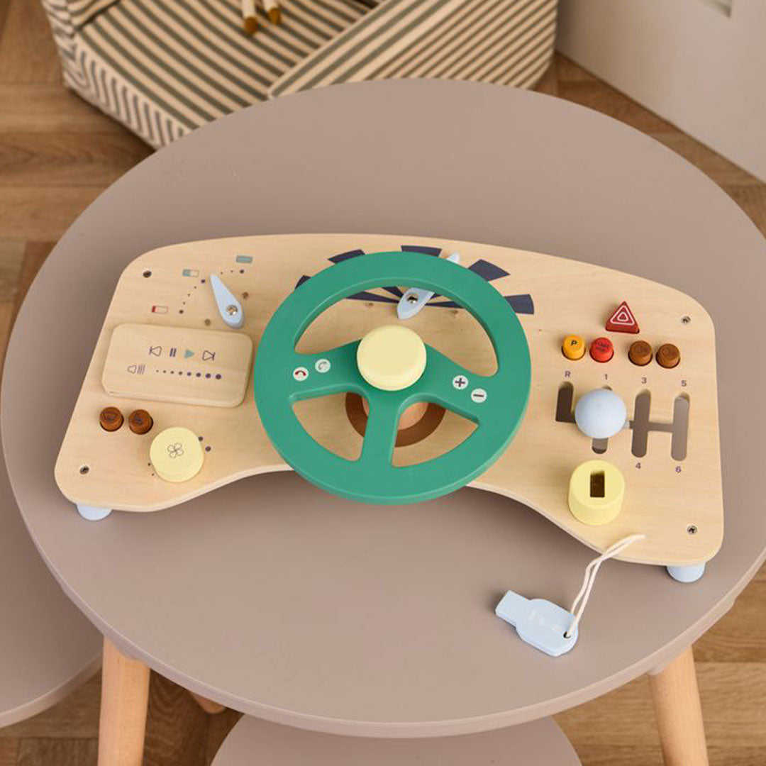 Kids Concept houten activiteitenpaneel auto op een kleine grijze ronde tafel, schuin gefotografeerd.