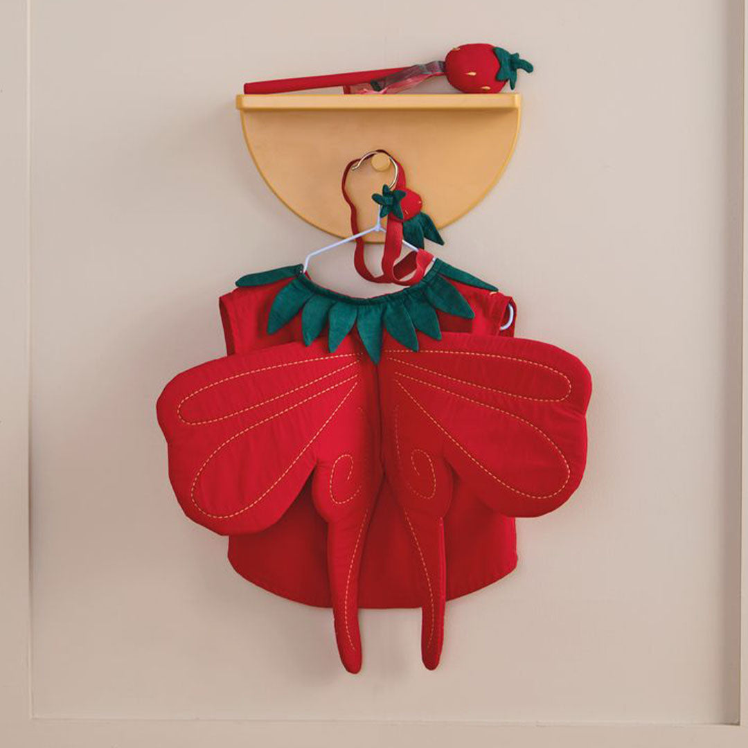 De achterkant van de Kids Concept aardbeienfee verkleedkleding set hangt aan een haakje aan de muur.