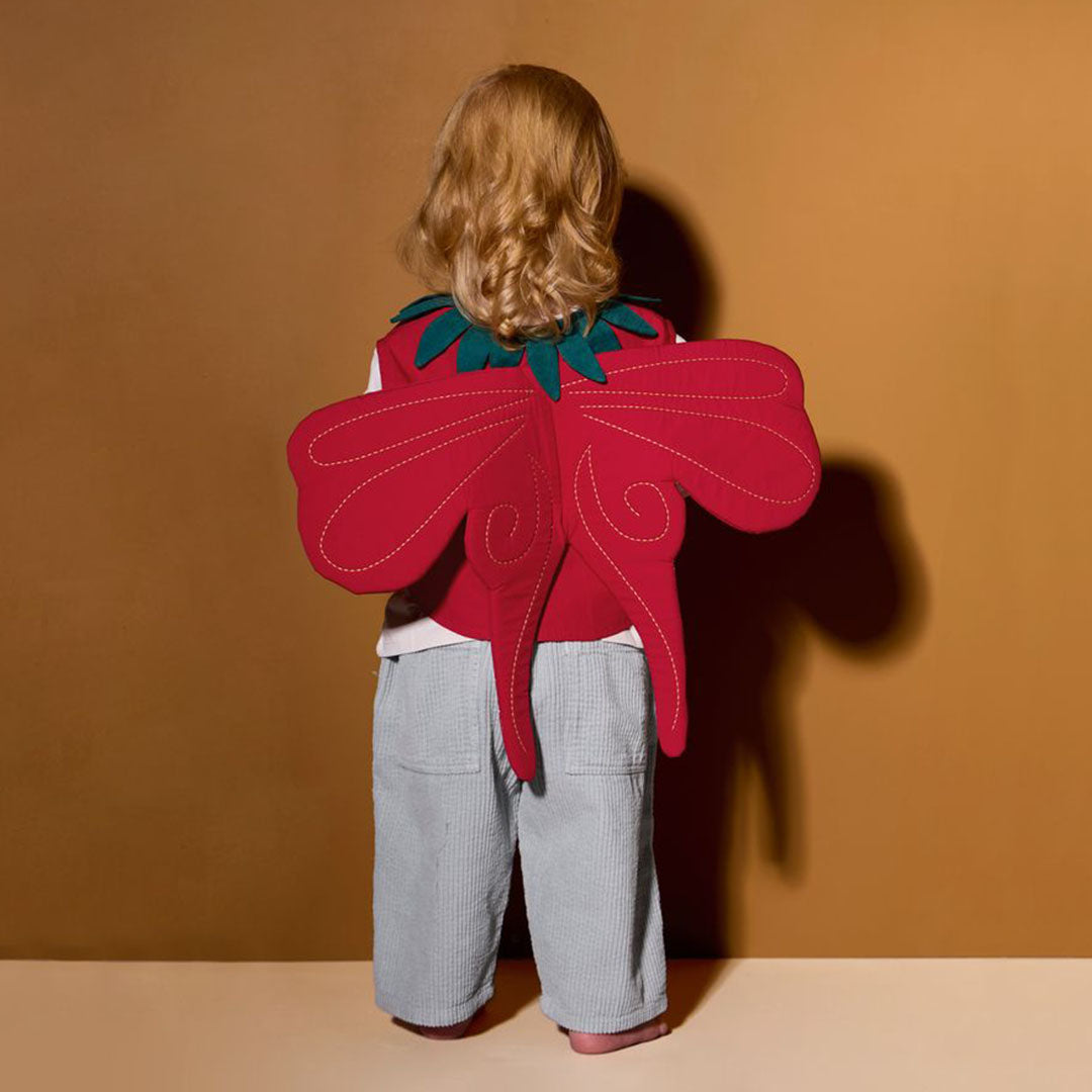 Een kind draagt van achteren gezien de Kids Concept aardbeienfee verkleedkleding met rode vleugels en groen blad.