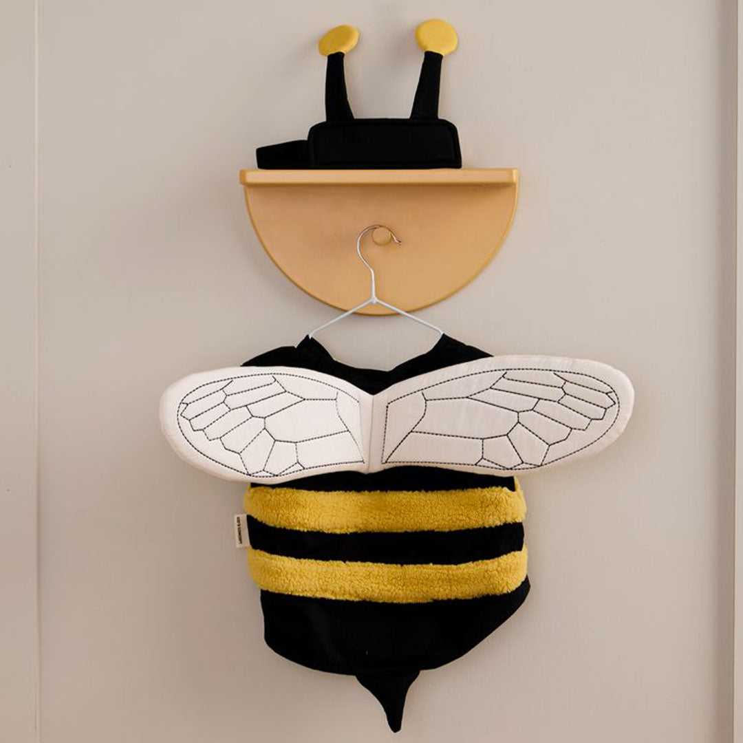 Kids Concept verkleedkleding hommel hangt met de achterkant naar voren aan een haakje aan de muur, met de vleugels en het gestreepte vest zichtbaar.