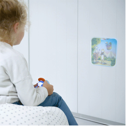 Een kind projecteert een afbeelding van een fabel op een witte muur met een Kidywolf projector zaklamp.