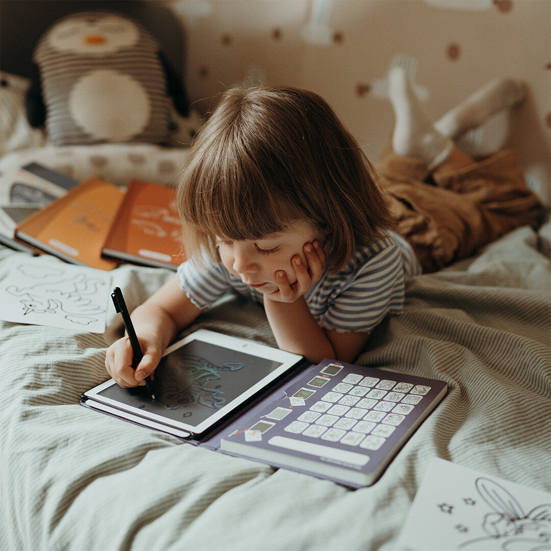 Een kind tekent liggend op bed met het Kidywolf KidyDraw Mini tekenbord.