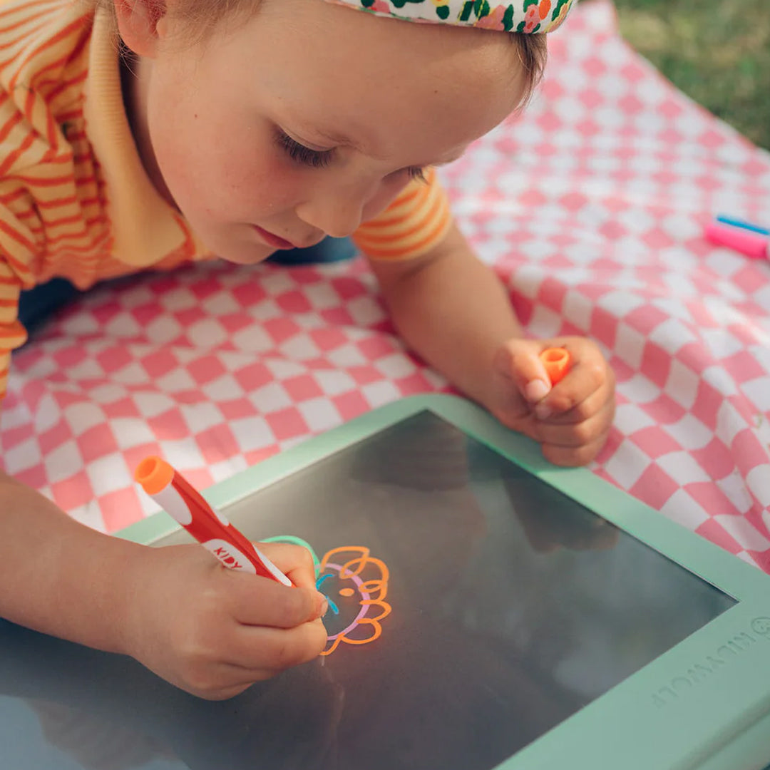 Een kind tekent met een oranje stift een kleurrijke figuur op het Kidywolf KidyDraw Pro tekenbord.