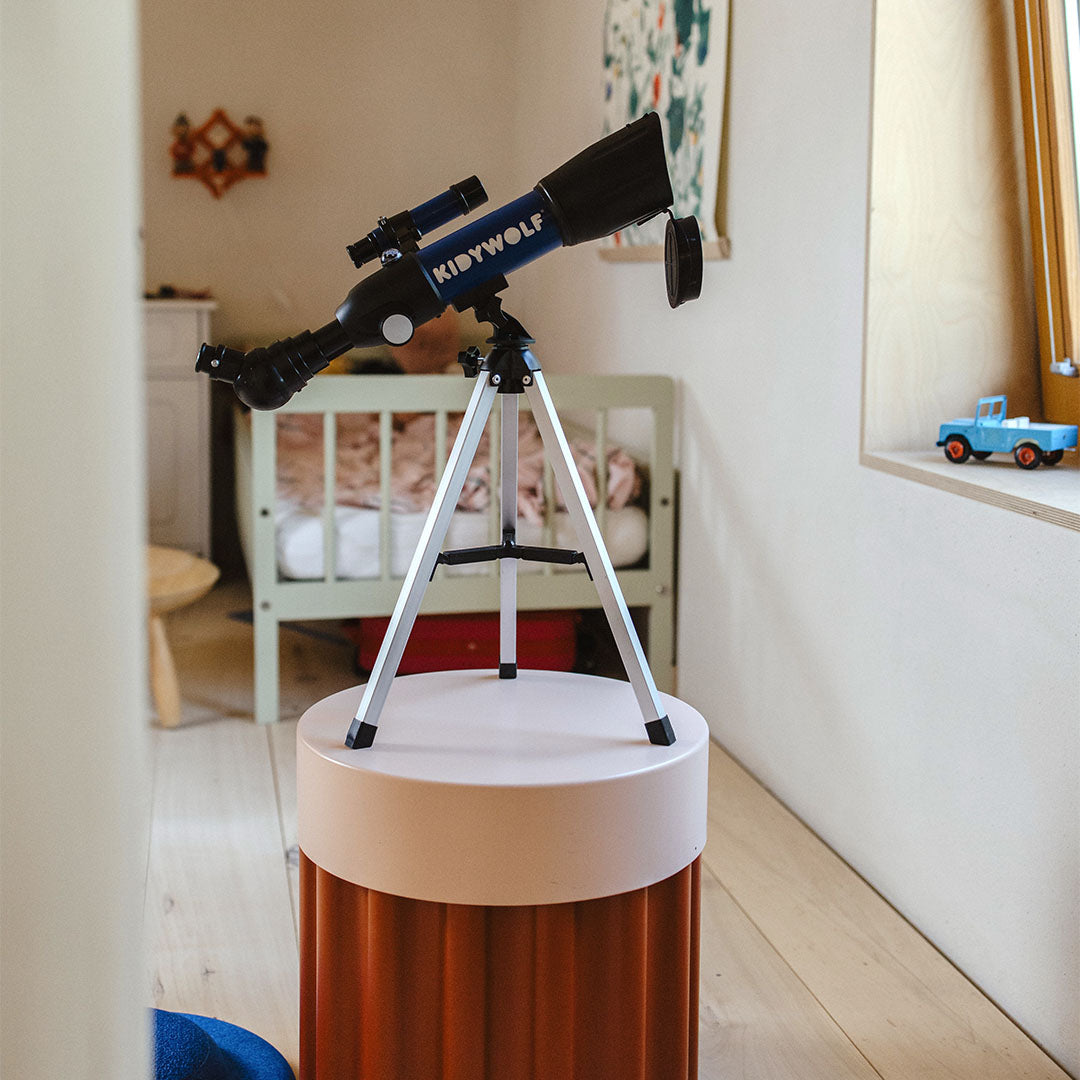 De Kidywolf telescoop op een statief staat op een rond voetstuk in een kamer.