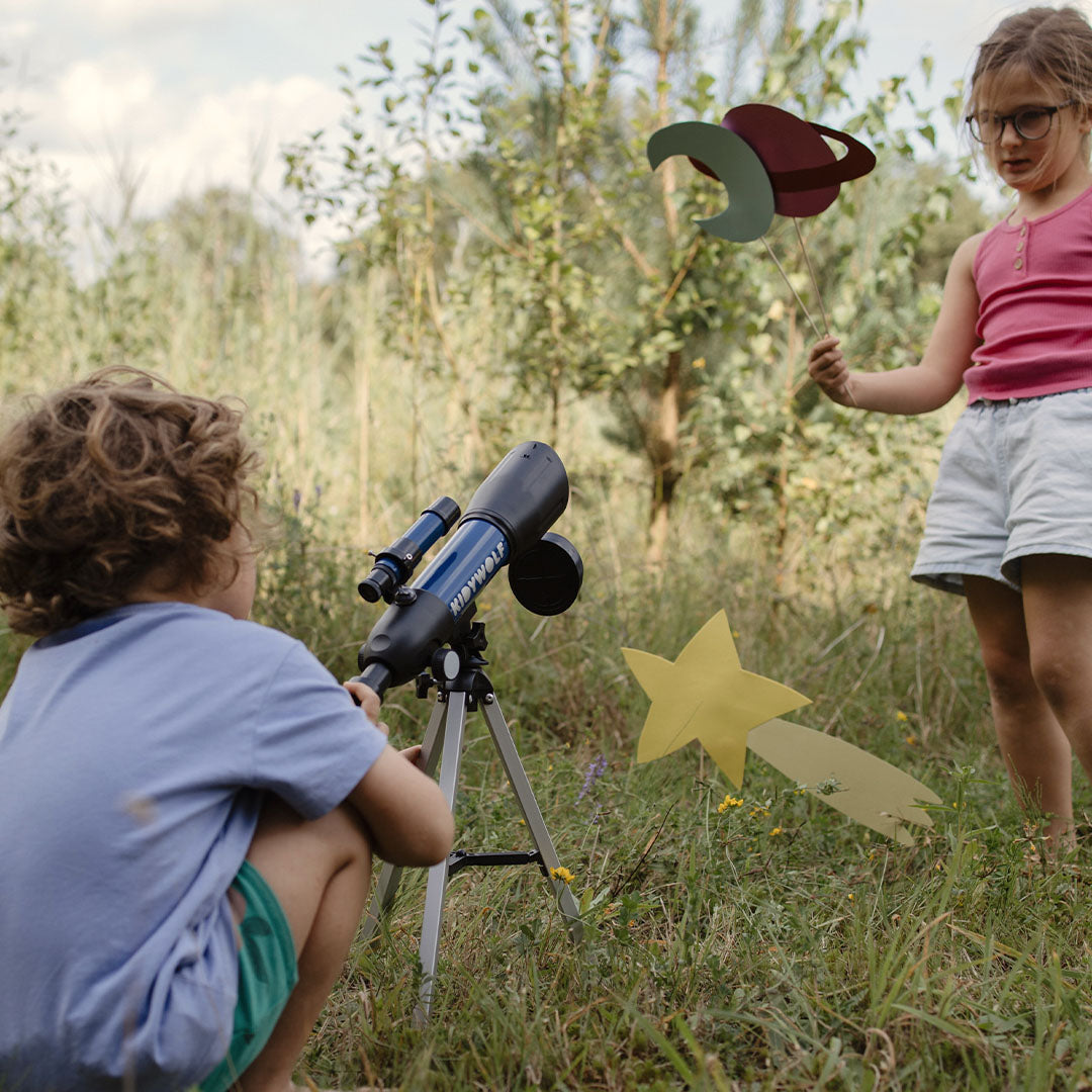 Twee kinderen spelen buiten met de Kidywolf telescoop en papieren planeten.