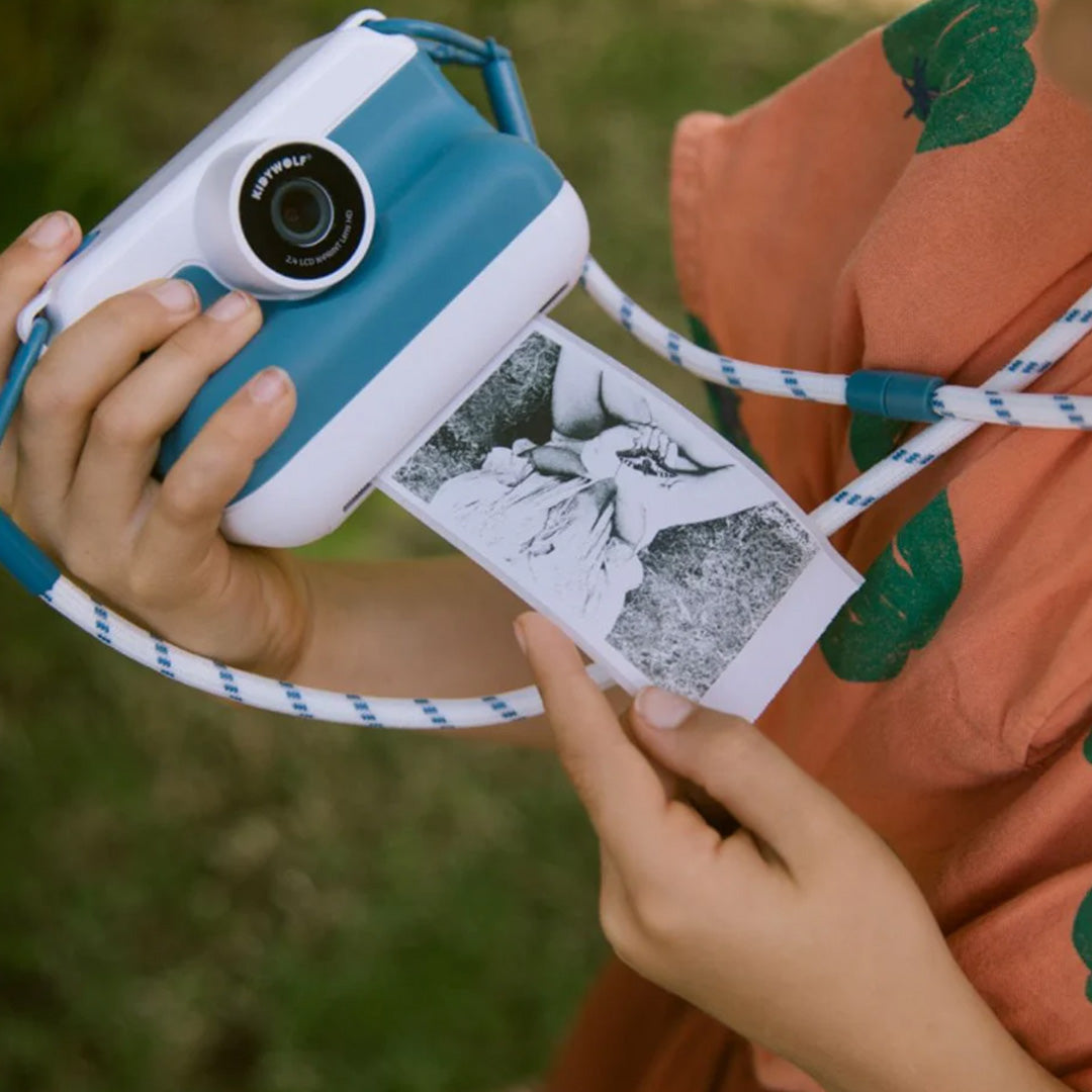Handen houden de Kidywolf kindercamera vast waar een zwart-witfoto uitkomt.