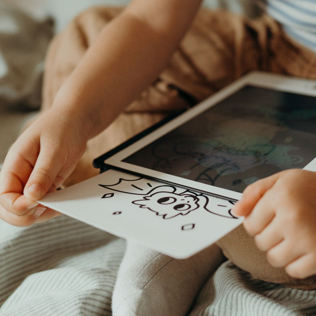 Kinderhanden schuiven een tekenkaart met een draak in een KidyDraw apparaat.