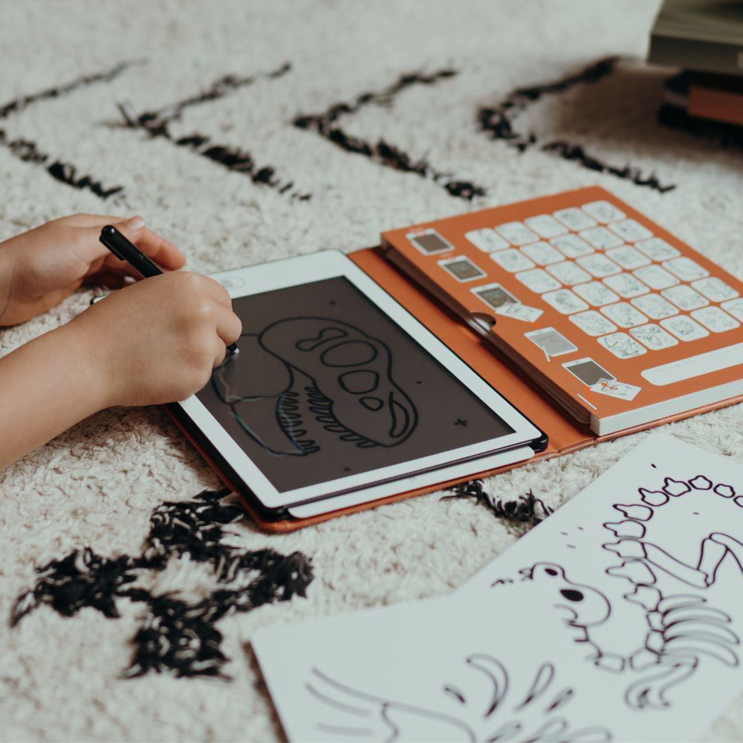 Kinderhanden tekenen een dinosaurus op een Kidywolf Kidydraw Mini tablet met een stylus.