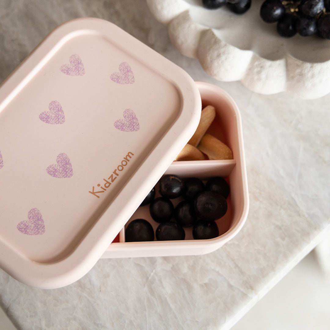 Kidzroom roze broodtrommel met hartenpatroon, open met druiven en koekjes in de vakjes.