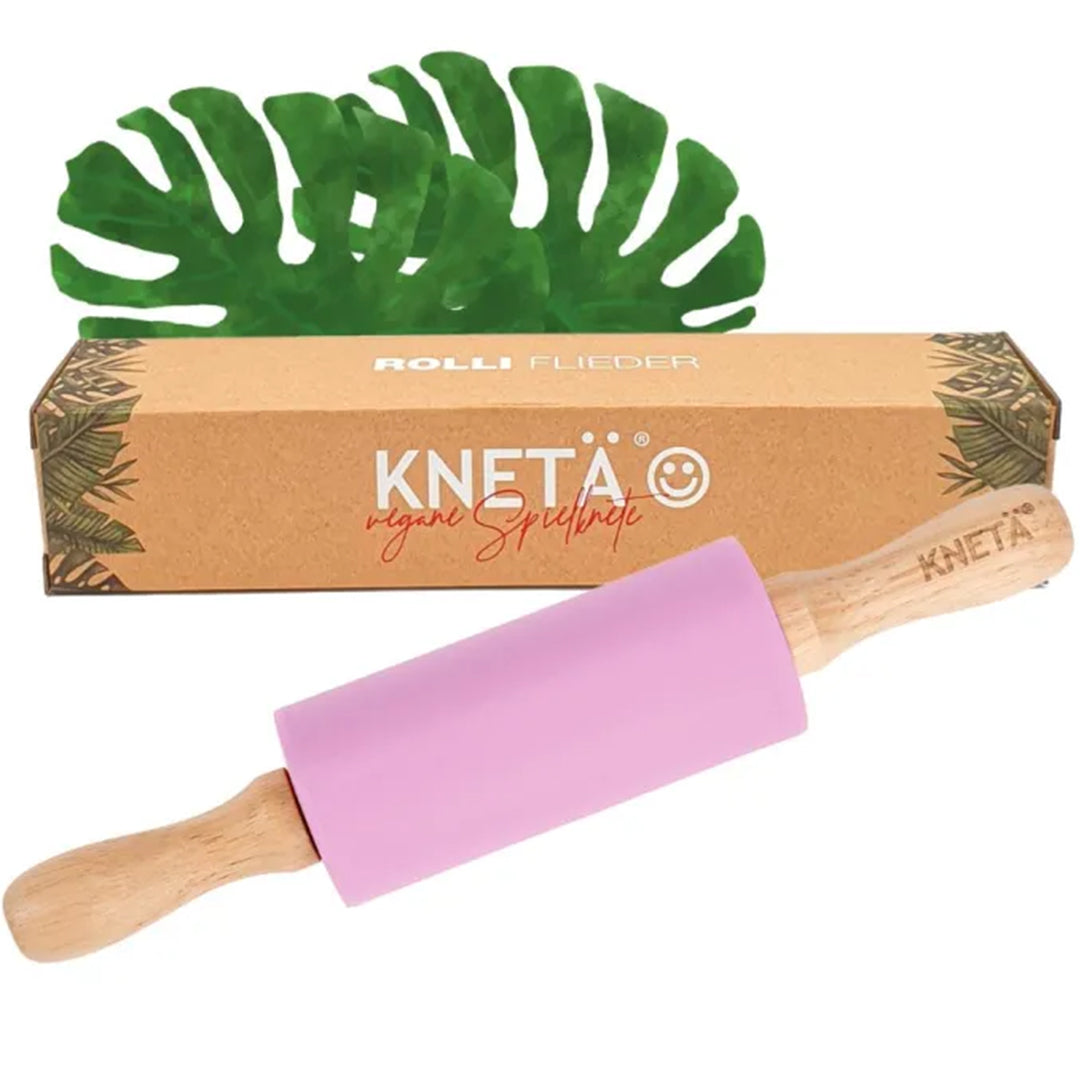 Knetä houten en siliconen roller in roze, met de verpakking en groene bladeren op de achtergrond.
