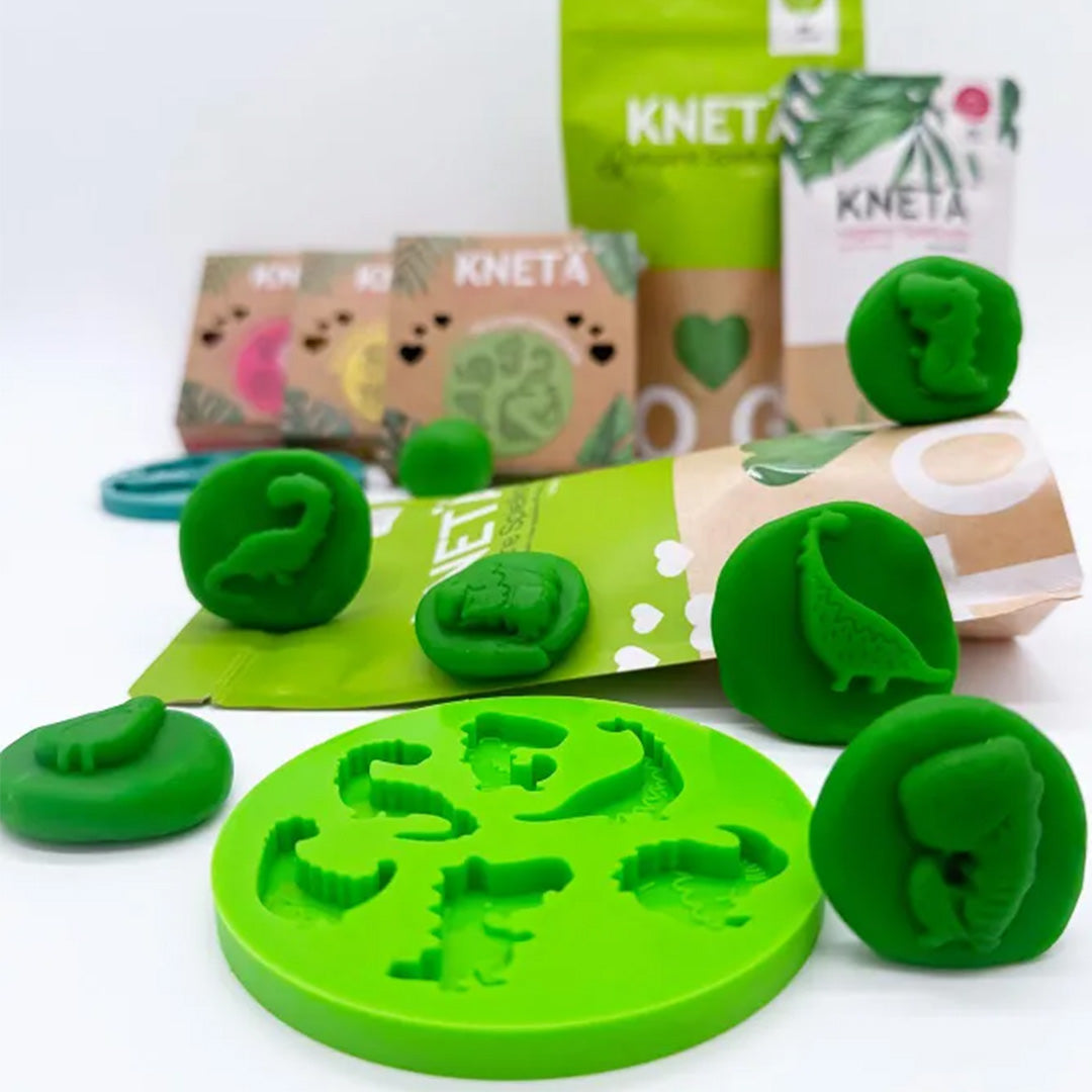Knetä groene siliconen dinosaurusvorm met groene klei en afdrukken van dinosaurussen, met verpakkingen op de achtergrond.