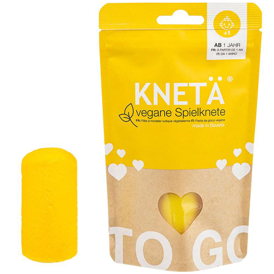 Een gele verpakking Knetä vegan speelklei naast een geel kleiblok.