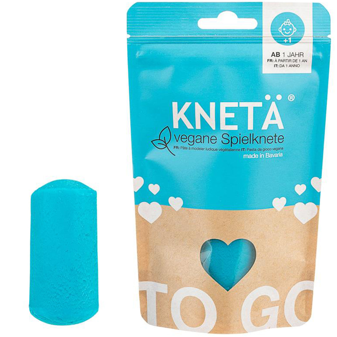Knetä vegane speelklei in turkoois kleur, naast de blauw-bruine verpakking met hartuitsparing.