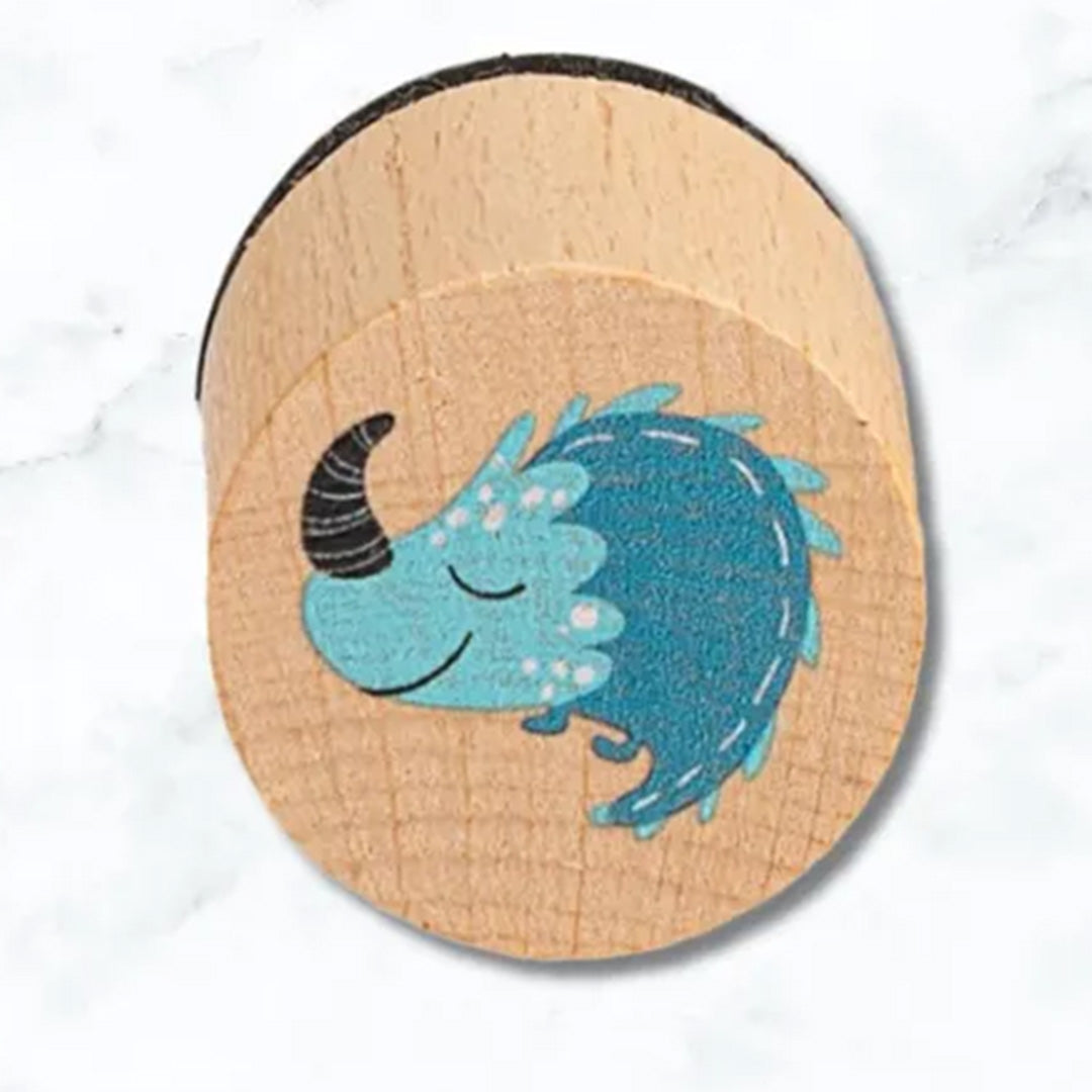 Detail van een houten stempel met een blauwe, stekelige dinosaurus.