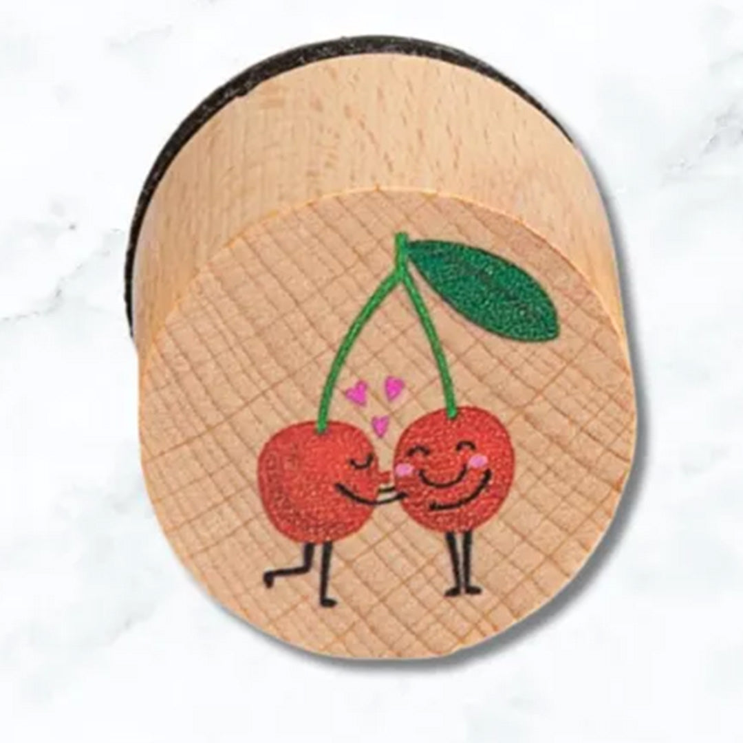Detail van een houten stempel met een illustratie van twee lachende kersen.