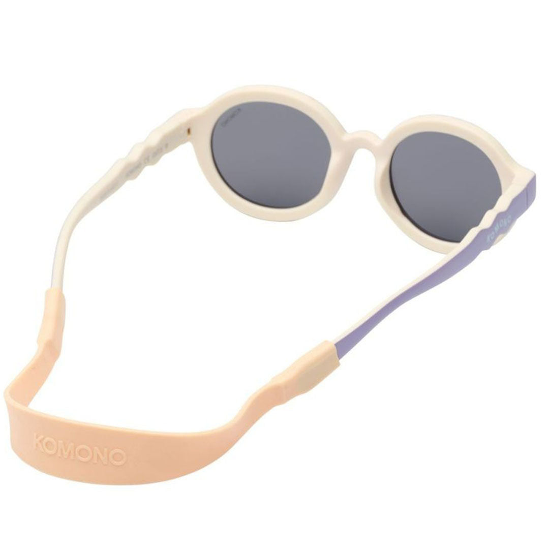 Komono babyzonnebril met crème montuur, paarse pootjes en een beige/roze verstelbaar bandje, van achteren gefotografeerd.