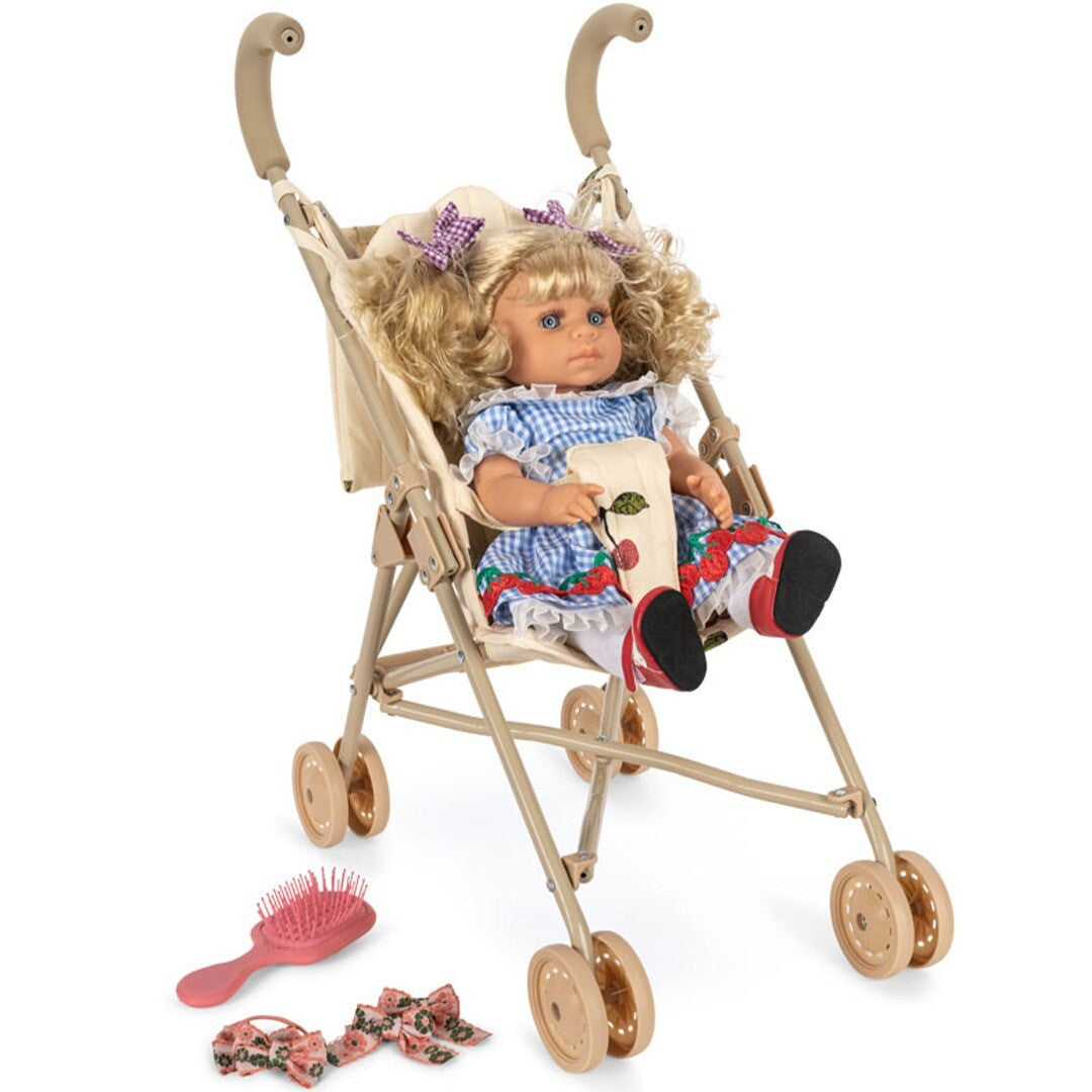 Konges Sløjd babypop Delphine zit in de uitgeklapte buggy, met de roze borstel en gebloemde haarstrikjes ernaast op de grond.