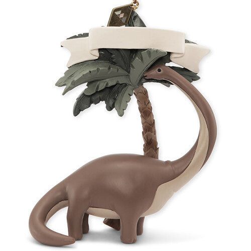 Konges Sløjd kersthanger van een bruine dinosaurus met een palmboom en een blanco banner.