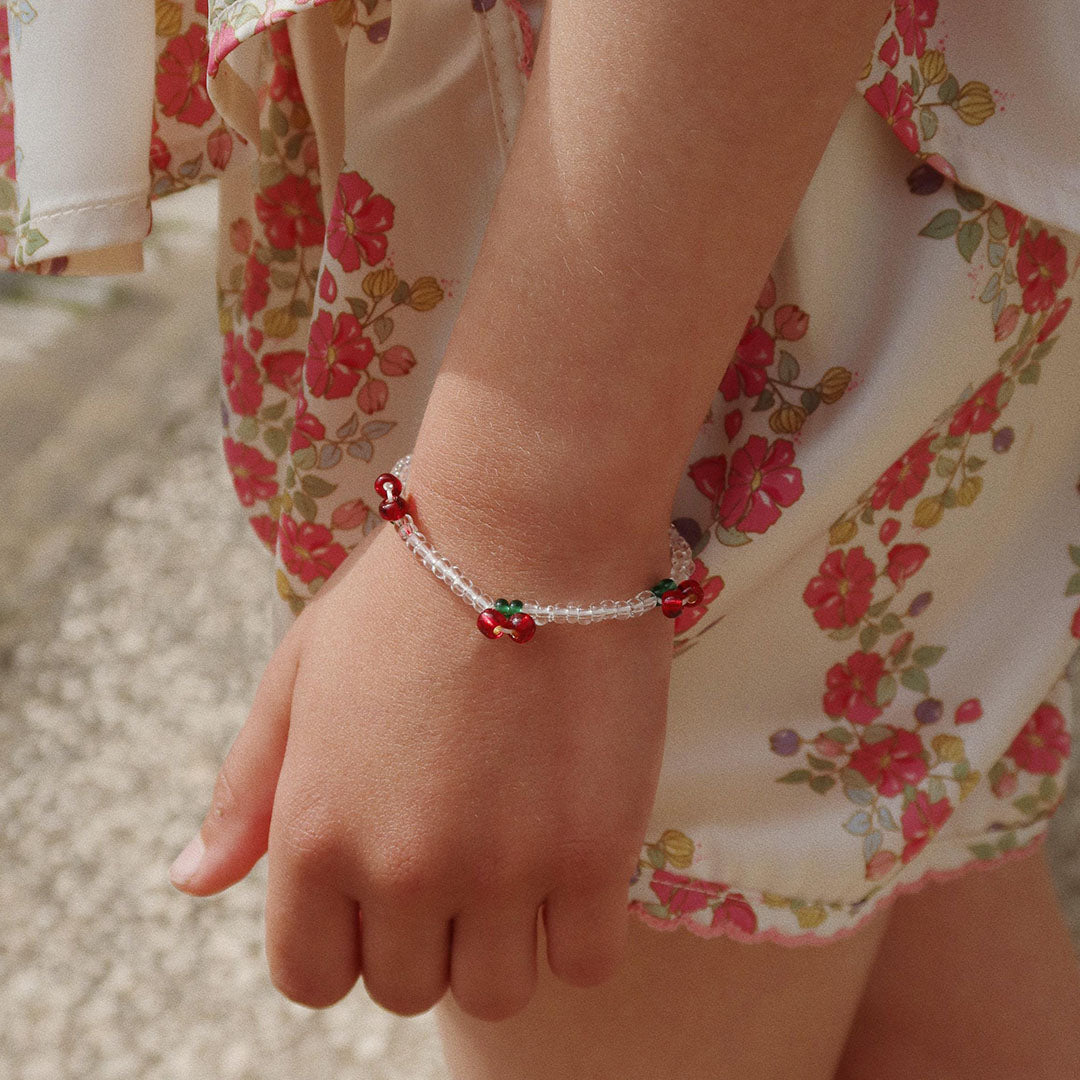 Een kind draagt de Konges Sløjd kinderarmband met kersjes om de pols.