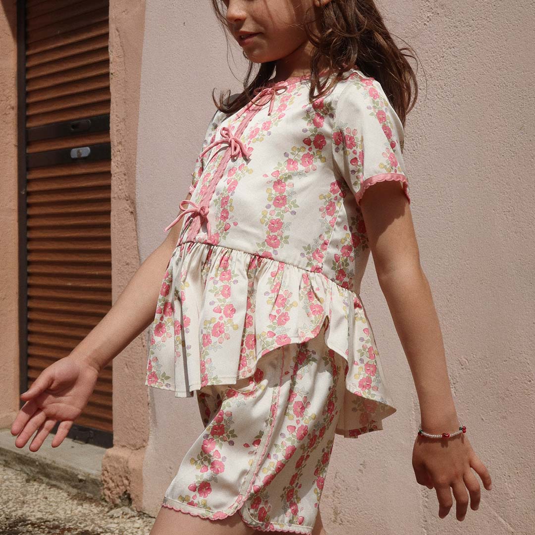 Een kind loopt buiten en draagt de Konges Sløjd kinderarmband met kersjes om de pols.