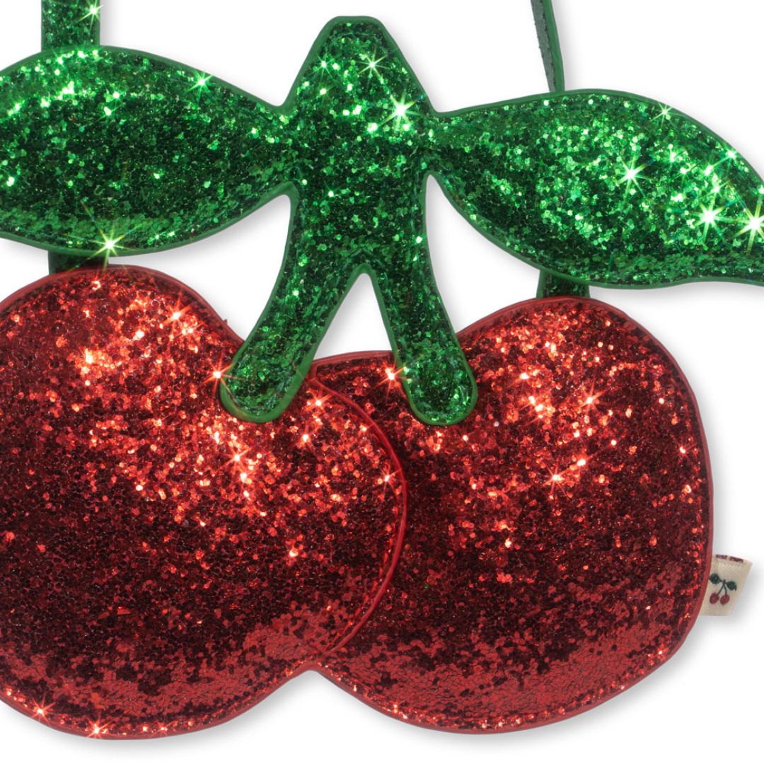 Detail van de rode glitter kersen en groene glitter bladeren van de kindertas.